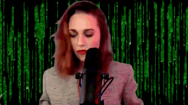 a woman is singing into a microphone in front of a green background with numbers .