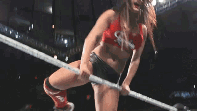 a woman in a red top and black shorts is wrestling in a ring .