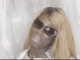 a close up of a woman wearing sunglasses and a white shirt .