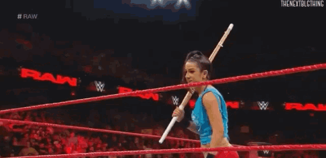 a woman is standing in a wrestling ring holding a spear .