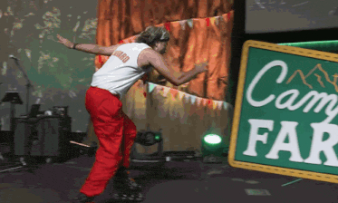 a man is dancing in front of a green sign that says camp far