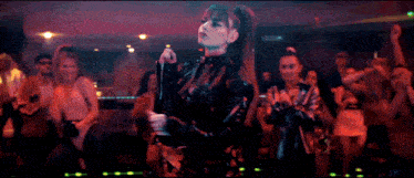 a woman in a black leather jacket is dancing in a club