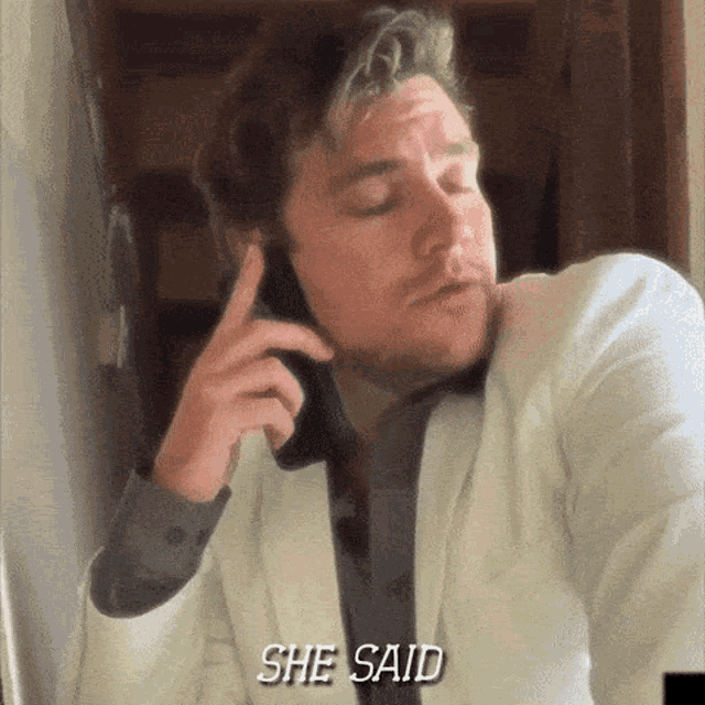 a man in a white suit is talking on a cell phone and the words she said are above him