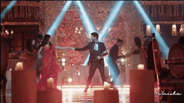 a man in a suit and bow tie is dancing with a woman in a red dress on a stage