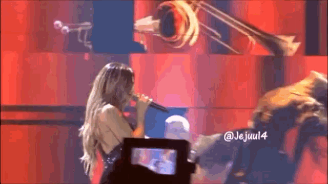 a woman singing into a microphone with the hashtag @ jejuul4 on the bottom right
