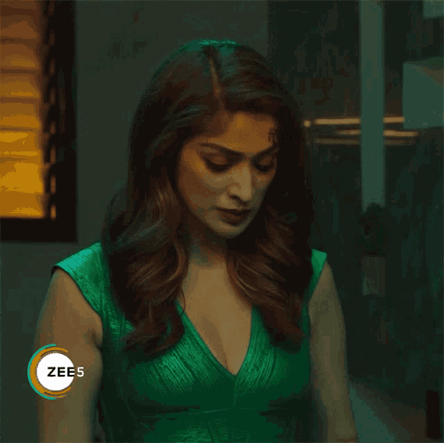 a woman in a green dress with a zees logo on her shoulder
