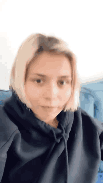 a woman wearing a black hoodie is sitting on a couch .