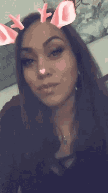 a close up of a woman wearing reindeer antlers and a heart on her nose