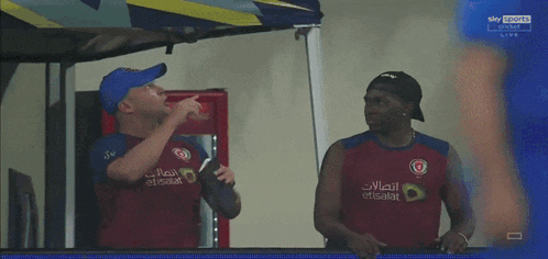 a man wearing a red shirt that says etisalat stands next to another man