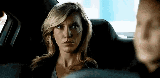 a woman is sitting in the back seat of a car looking at the camera .
