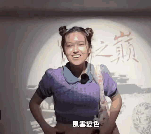 a woman in a purple shirt stands in front of a wall with chinese characters on it
