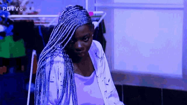 a woman with blue braids is sitting in front of a purple background with pdtv6 written on it