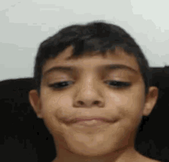 a close up of a young boy making a funny face while sitting on a couch .