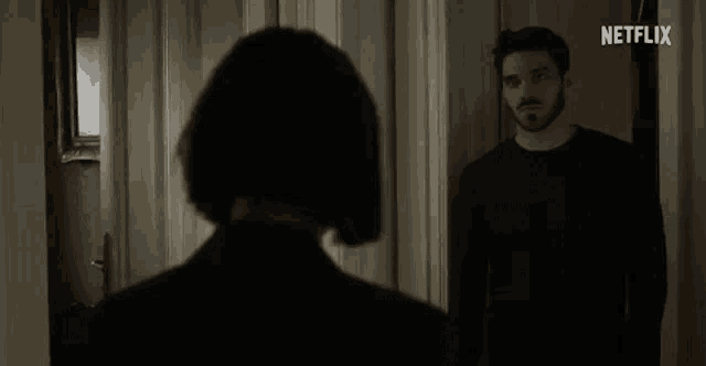 a man and a woman are standing next to each other in a hallway in a dark room .