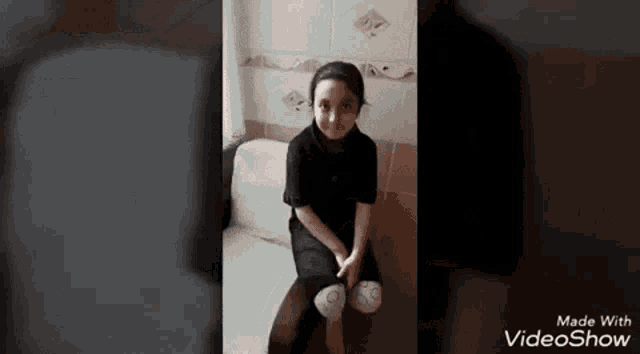 a little girl is sitting on a toilet with her legs crossed and smiling .