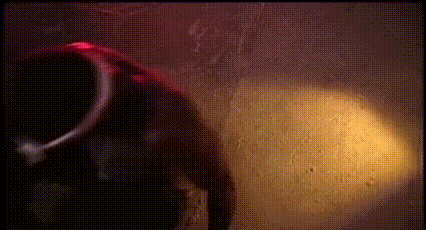 a person in a hooded jacket is standing in a dark room with a red light behind them .