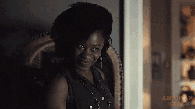 a woman sitting in a chair with the words american gods written on the bottom