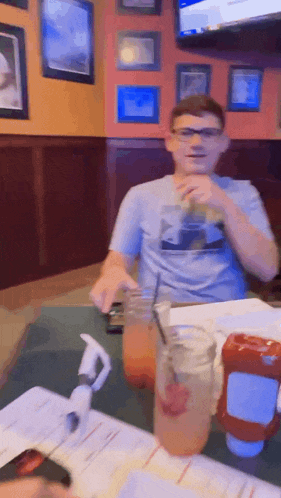 a man sitting at a table with a drink and ketchup on it