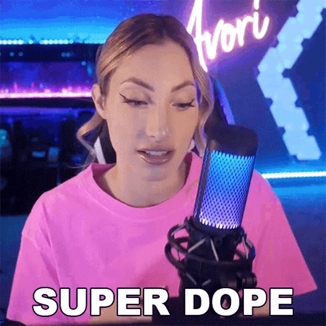 a woman in a pink shirt is talking into a microphone and saying super dope