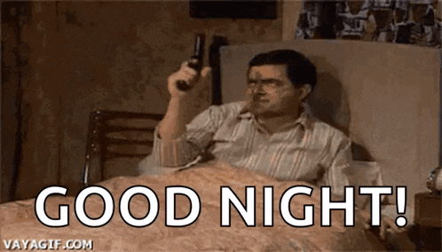 a man is laying in a bed holding a remote control and saying `` good night '' .