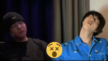 a man in a black hat and a man in a blue shirt are standing next to each other in a room .
