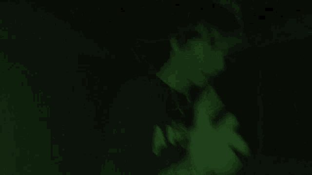 a person is standing in the dark with a green background