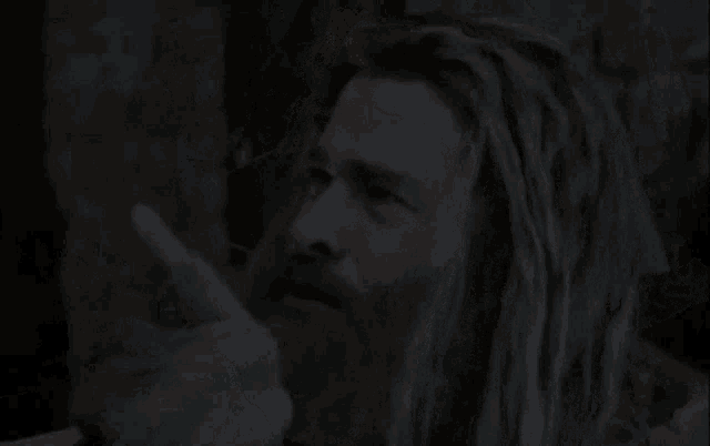 a man with long hair and a beard is pointing his finger