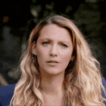a close up of a woman 's face with long blonde hair and blue eyes