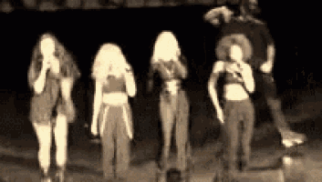 a group of women are singing into microphones on a stage in a black and white photo .