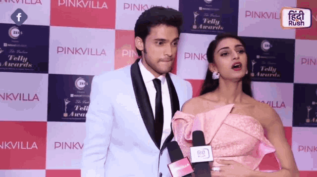a man and woman are standing in front of a wall that says pinkvilla on it