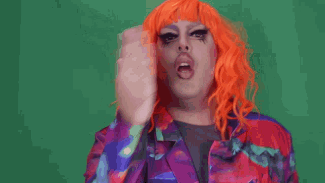 a drag queen with bright orange hair is making a face