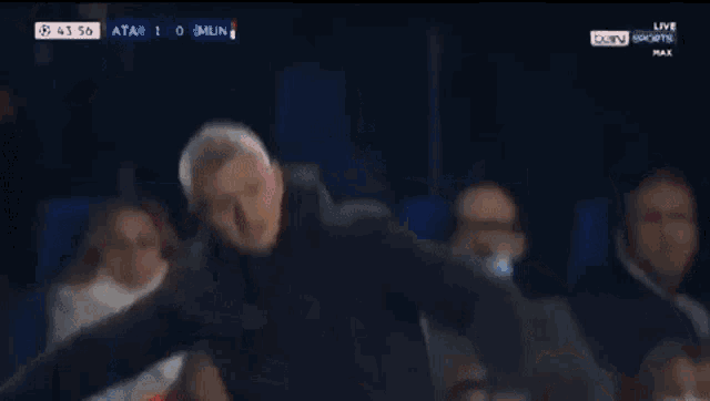 a man in a black jacket stands in front of a soccer player in a red shirt