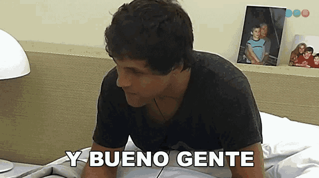 a man sitting on a bed with y bueno gente written on the bottom