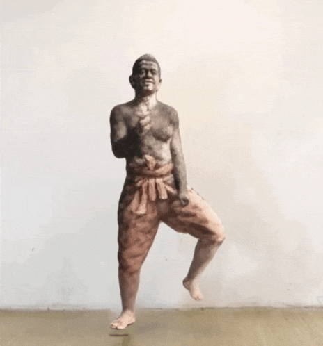 a statue of a man standing on one leg with a fist in the air