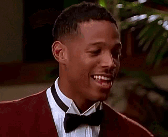 a man in a tuxedo and bow tie is standing next to another man in a white shirt .