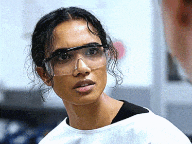 a woman wearing a white shirt and clear safety goggles