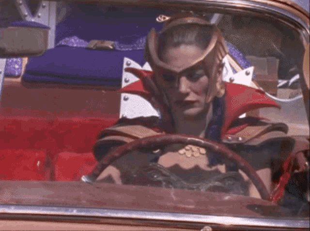 a woman in a costume is driving a car with a steering wheel