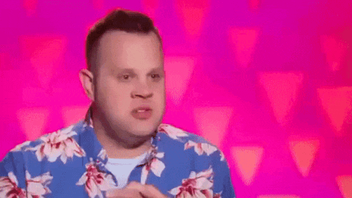 a man is applying makeup to another man 's face in a room with a pink wall .