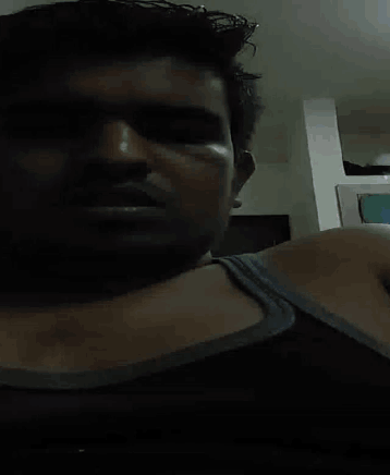 a man in a blue tank top looks at the camera with his eyes closed