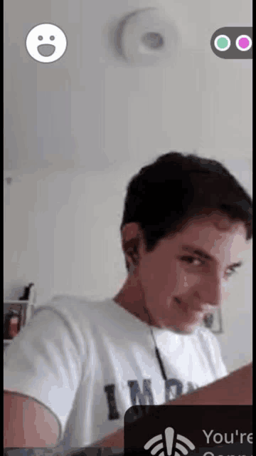 a young man wearing a white shirt that says i 'm on it is smiling while looking at a laptop .