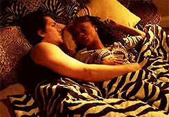 a man and a woman are laying in bed with a zebra print blanket .