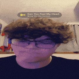 a young man wearing glasses and a black shirt is listening to can you feel my heart