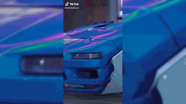 a black toyo tires car is driving down a street at night .