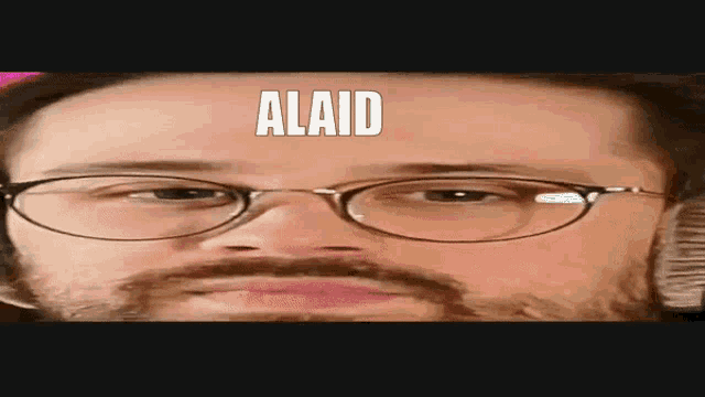 a man with glasses and a beard is making a funny face with the word alaid on his forehead .