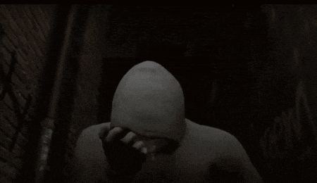 a man in a hoodie is standing in front of a brick wall and asking where am i
