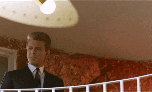 a man in a suit and tie standing on a balcony