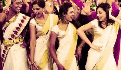 a group of women in saris are standing next to each other dancing .