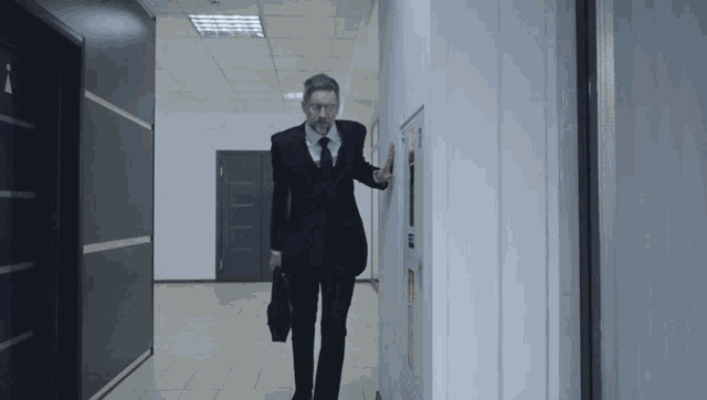 a man in a suit walking down a hallway