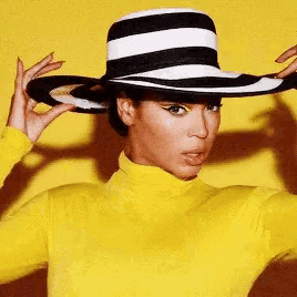a woman wearing a striped hat and a yellow turtleneck