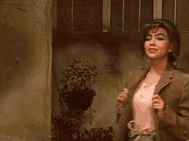 a woman in a brown jacket is standing in front of a wall .